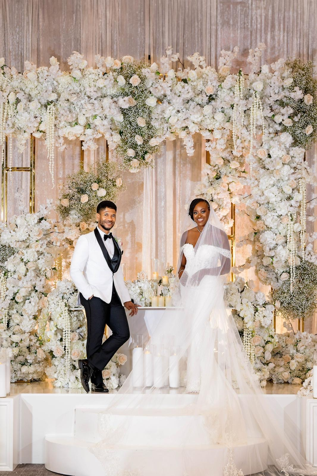 Bride and groom in front of luxurious floral arch